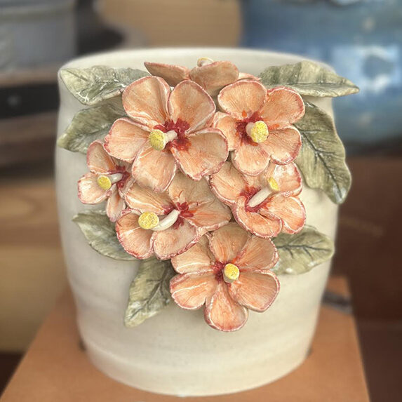 Pottery with heavily textured flowers in salmon, sage and white with a blurred background